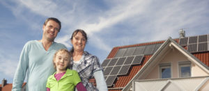 Happy family standing in front of house with solar panels